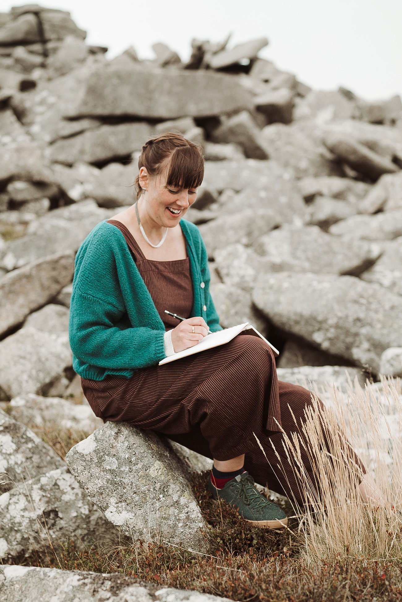 Corrinne Eira Evans sitting on a rock designing jewellery