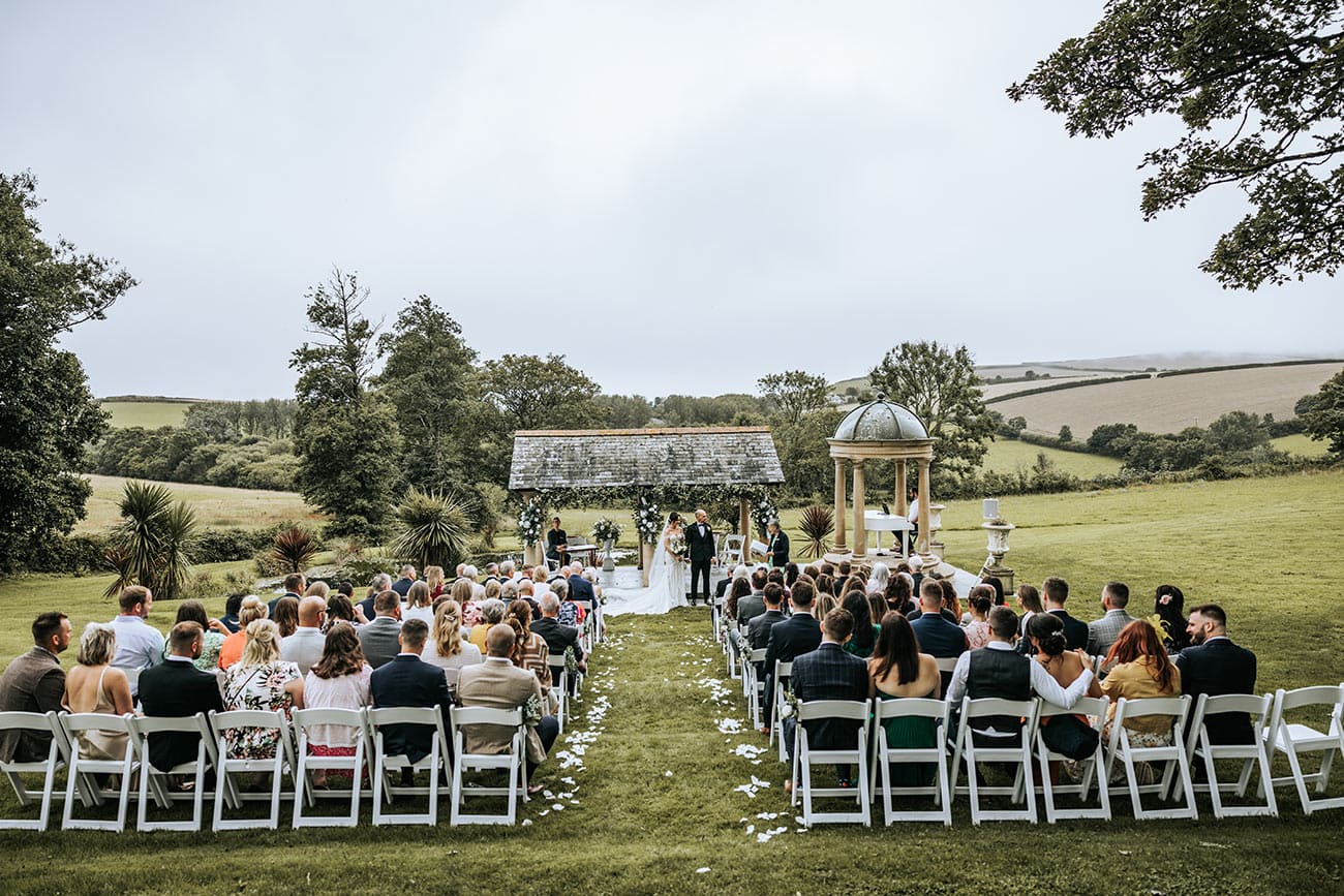Bride and groom in their outdoor ceremony with their wedding guests watching on