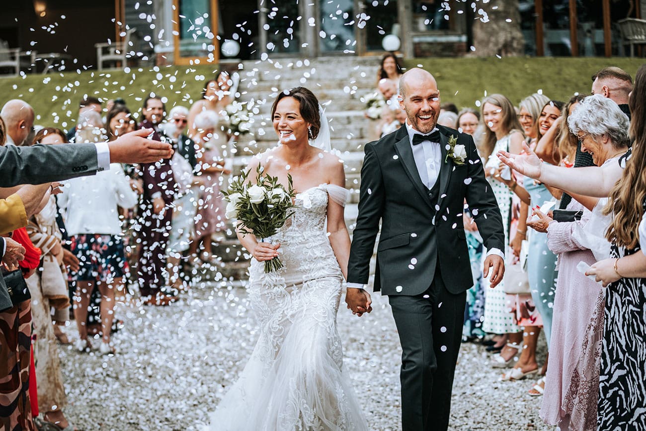 Bride and groom being showered with confetti by their guests