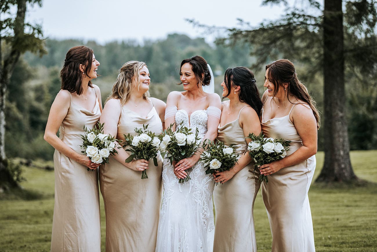 The bride with her bridesmaids in bronze dresses, all holding their bouquets