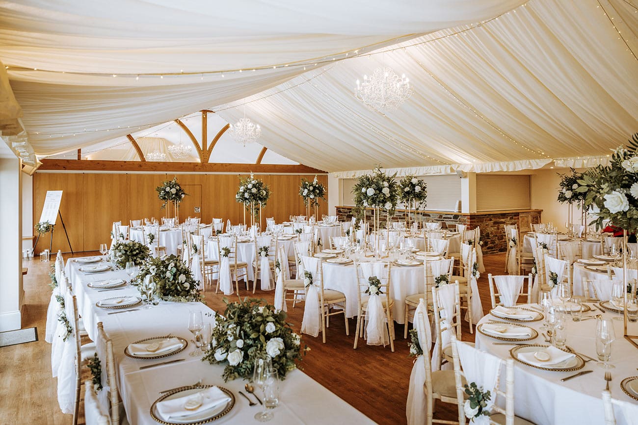 The reception room all set with white clothed tables laid out and floral centrepieces