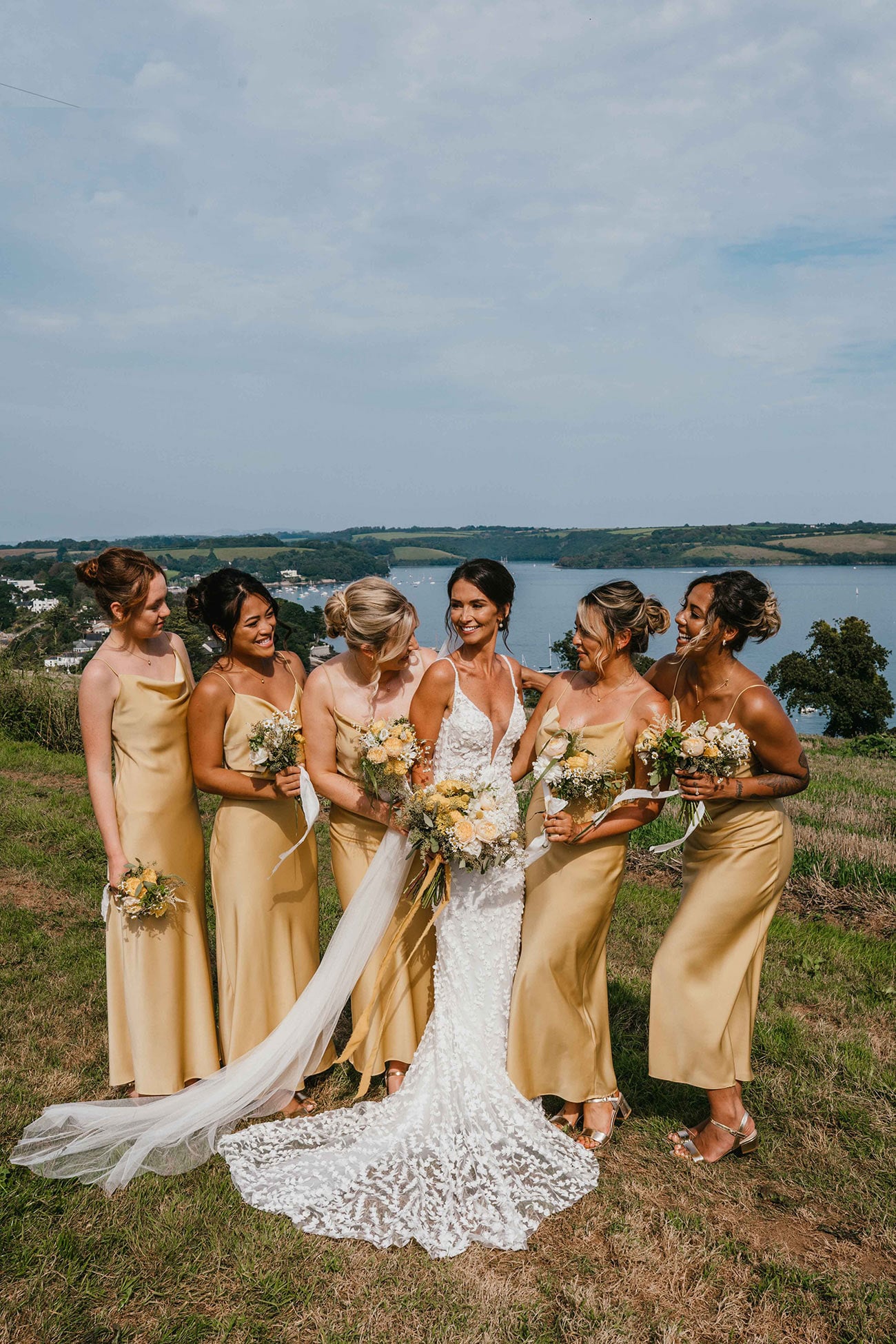 The bride smiles with her four bridesmaids who are dressed in gold