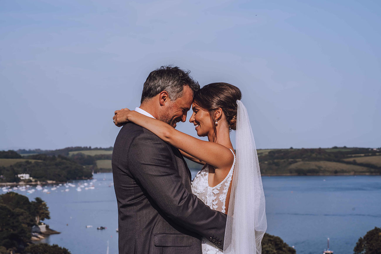 The bride and groom embrace with a stunning coastal backdrop 