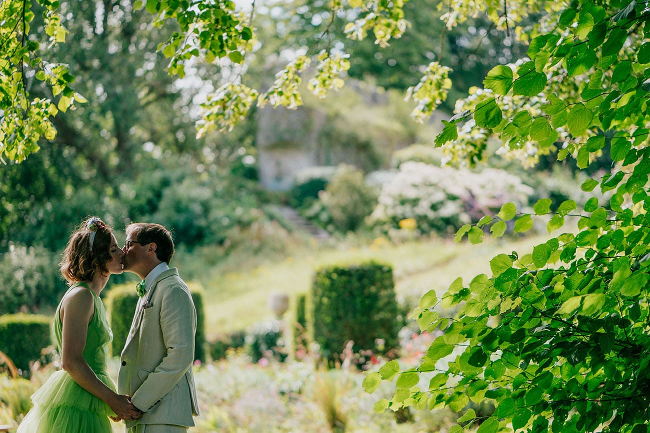 bride in her green bridal gown and groom kiss in the beautiful gardens 