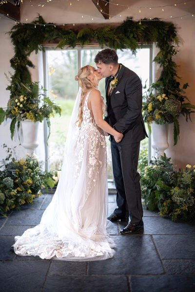 Bride and Groom kissing with floral background