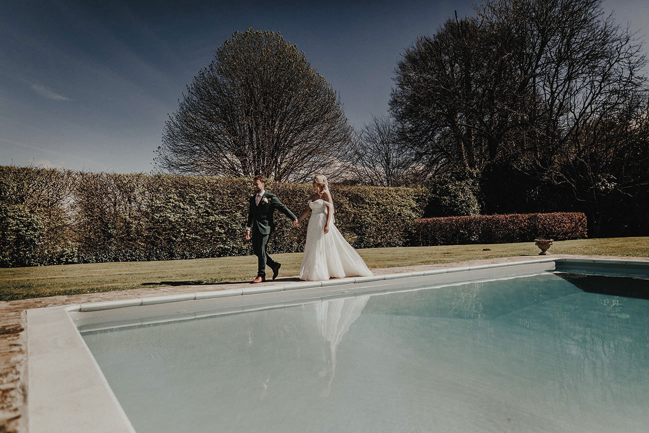 Bride and groom walking by a swimming pool