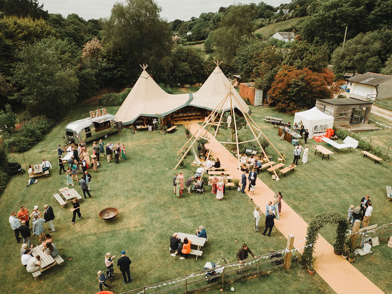 Drone footage of the wedding venue with the tipi, airstream bar and the wedding party and guests