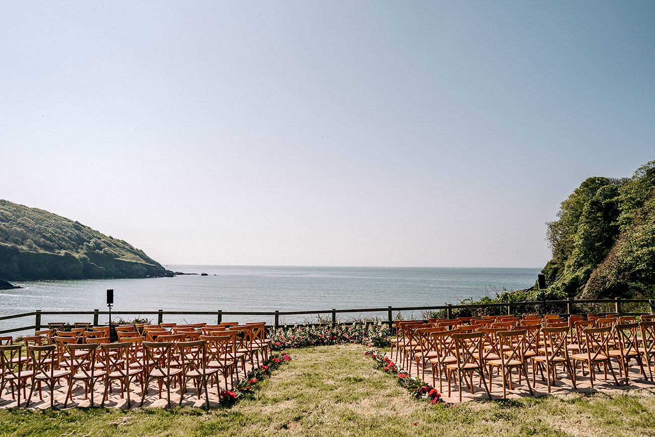 Outside ceremony set up with wooden chairs with a stunning sea view