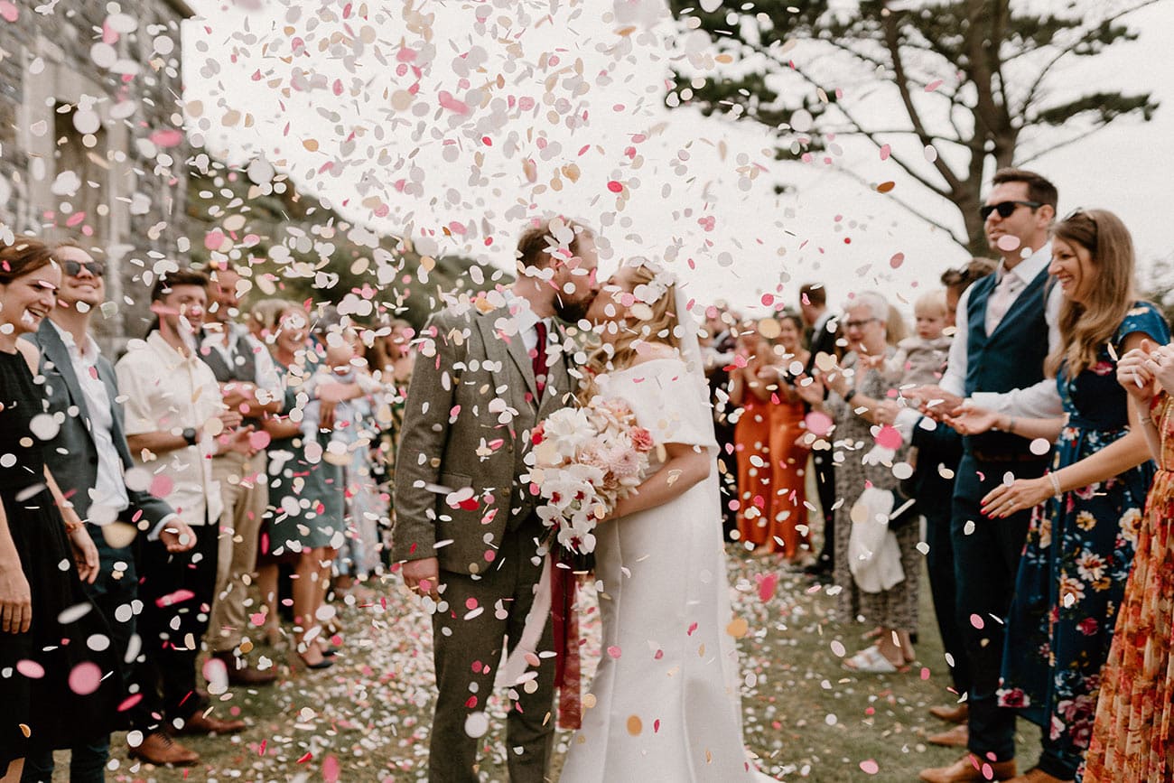 bride and groom having a kiss under confetti