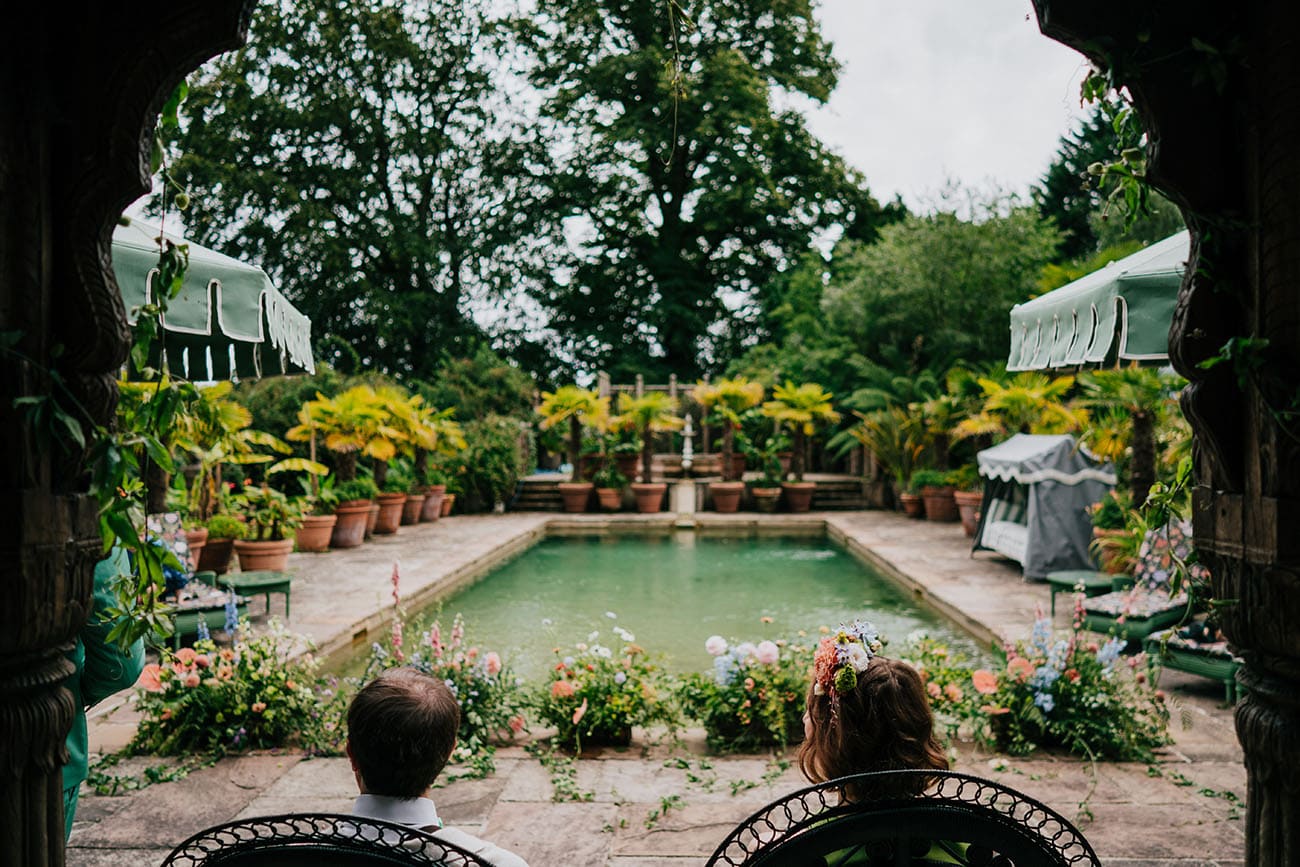 Bride and groom look upon their unique outdoor wedding venue that also includes an outdoor pool