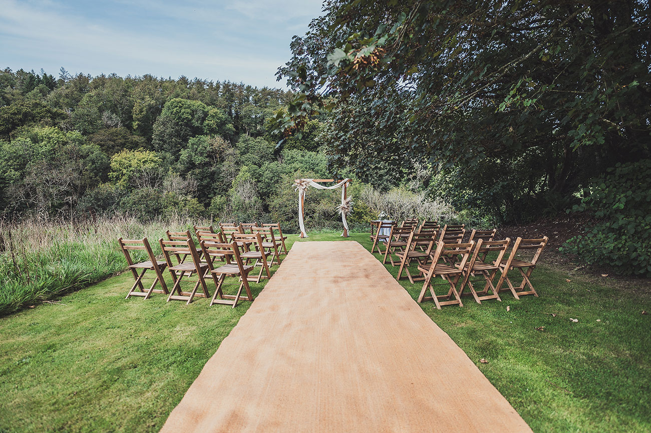 Wedding ceremony outside with wooden chairs and arch